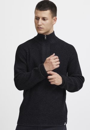 Schwarzer Reißverschluss-Pullover mit einem strukturierten, gerippten Muster. Verfügt über lange Ärmel und einen hohen Kragen mit einem silbernen Reißverschluss. Lässiger Schnitt.