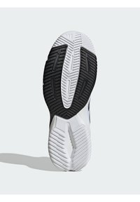 Podeszwa buta z białym i czarnym gumowym wzorem, z teksturowanymi wzorami i rowkami zapewniającymi przyczepność. Centralne wycięcie dla elastyczności.