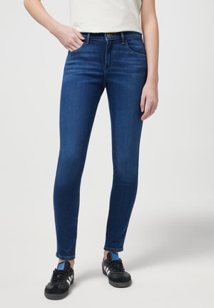 Skinny jeans made of dark blue denim featuring a smooth texture, five-pocket design, and a button closure at the waist.