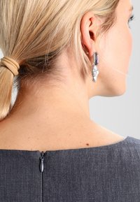 Jeanskleid mit rundem Ausschnitt und einem diskreten Reißverschluss auf der Rückseite; zeichnet sich durch eine glatte Textur und eine figurnahe Silhouette aus.