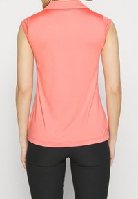 Korallfärgad ärmlös polo-top med krage, tillverkad av ett glatt tyg; har en figursydd design och subtila sömnadsdetaljer längs kanten.