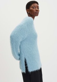 Hellblaues, flauschiges Sweatshirt mit lockerer Passform, langen Ärmeln und seitlichen Schlitzen. Aus einem weichen, strukturierten Material für zusätzlichen Komfort gefertigt.
