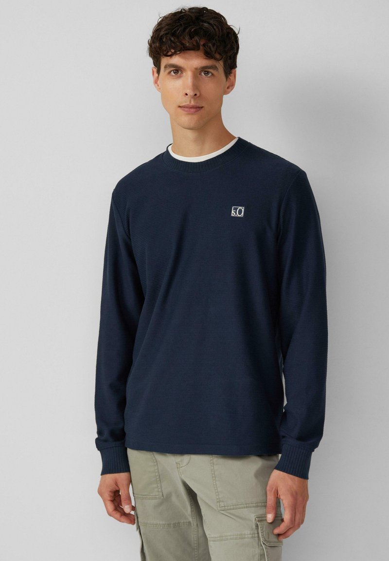 Maglione a maniche lunghe blu navy con collo a giro e polsini a coste. Presenta un piccolo logo sul petto. Realizzato in tessuto testurizzato.