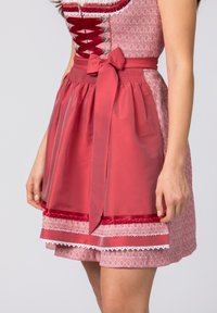 Rotes Kleid mit Muster, eng anliegendem Oberteil, Spitzenbesatz und schwingendem Rock. Enthält eine passende rote Schürze, die mit einer Schleife in der Taille gebunden ist.