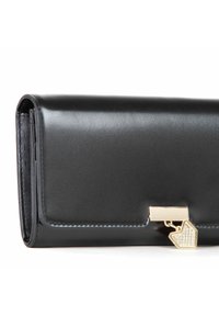 Billetera de cuero negro con un acabado suave, que presenta un cierre dorado y un charm decorativo en forma de corazón adornado con rhinestones.