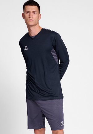 T-shirt de sport à manches longues bleu marine avec des accents gris, col en V et logo. Associé à un short de sport gris pour une tenue sportive complète.