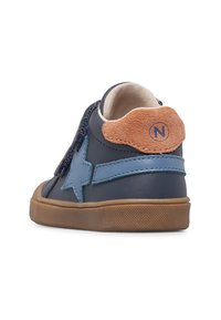 La scarpa alta in pelle blu navy presenta un dettaglio a stella blu, un accento in suede beige sul tallone e una suola in gomma marrone con grip testurizzato.