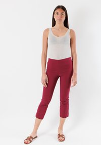Top aderente grigio e pantaloni cropped bordeaux. Tessuto morbido, colori solidi, design minimal e scollatura semplice. Sandali piatti marroni.