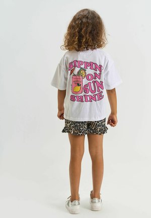 Wit T-shirt met opschrift "Sippin' on Sunshine" en een afbeelding van een drankje en fruit. Gecombineerd met shorts in luipaardprint met een gerimpelde zoom.