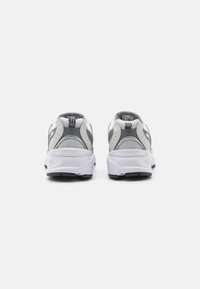 Grijze en witte sport schoenen van gaas materiaal, rond model, gevoerde kraag en rubberen zool. Heeft contrasterende accenten aan de zijkanten.