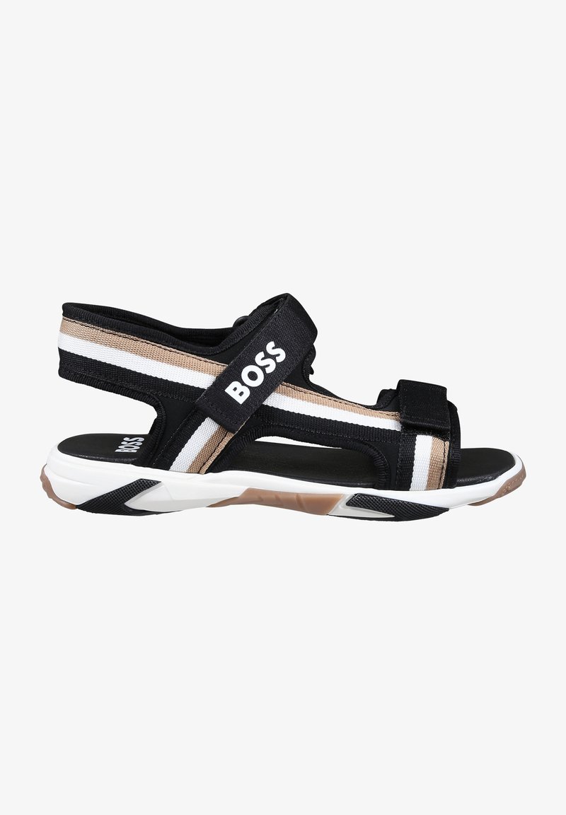 Sandales noires et beiges avec des sangles réglables en velcro, une semelle rembourrée et une semelle en caoutchouc avec un motif texturé. Logo de la marque visible.