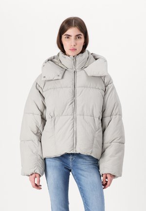 Veste matelassée gris clair avec un col haut, des boutons-pression et une coupe courte. Texture matelassée, présentant de larges manches et une fermeture éclair.