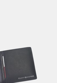 Portafoglio in pelle nera con una texture liscia, dotato di uno slot per carte e logo impresso nell'angolo in basso a destra.