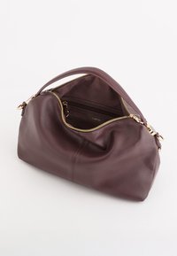 Brązowa skórzana torebka o miękkim, zaokrąglonym kształcie i górnym zamkiem błyskawicznym. Akcenty złotego hardware'u z widoczną wewnętrzną kieszonką.