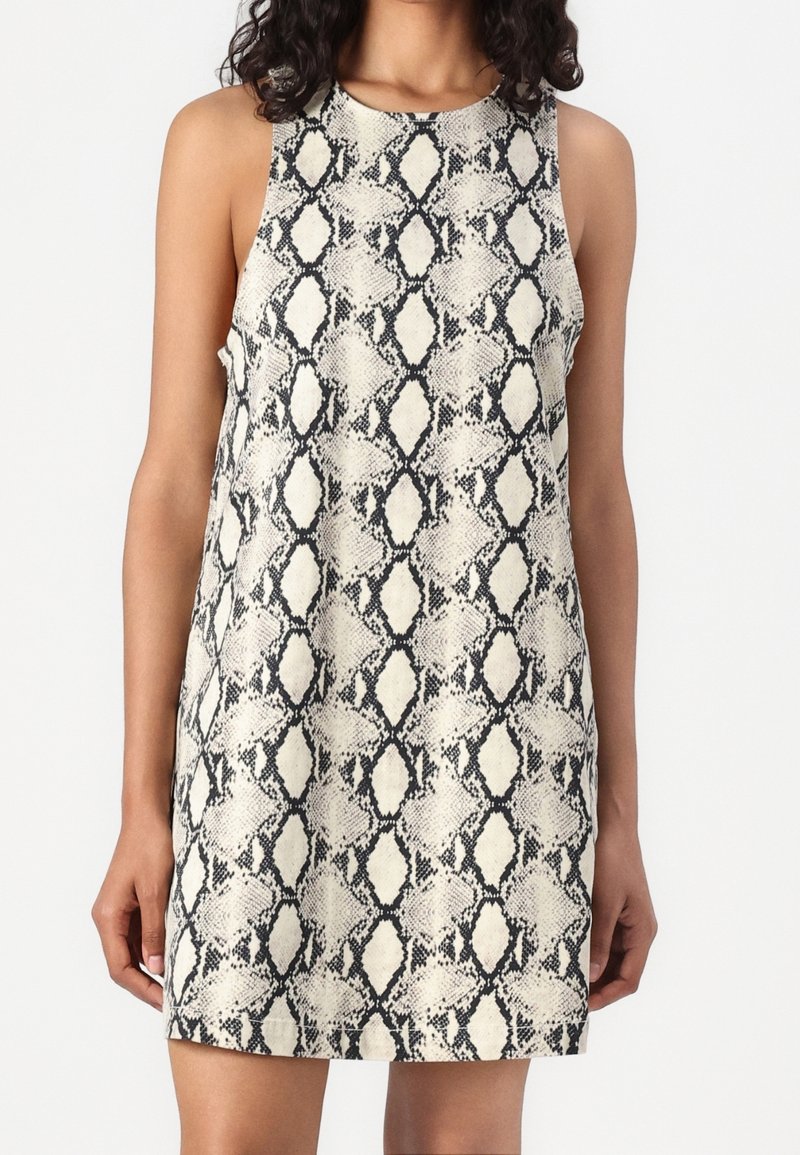 Robe sans manches avec imprimé serpent noir et blanc, ajustée sur le haut et légèrement évasée dans l'ourlet, portée par une personne.