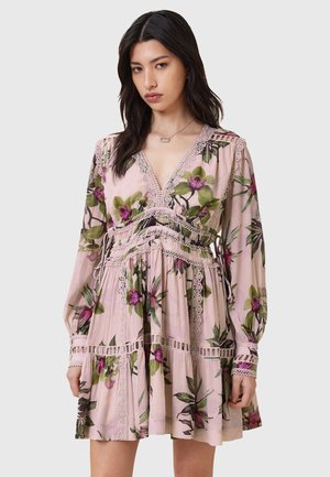 Blumenkleid in zartem Rosa mit langen Ärmeln, V-Ausschnitt, Spitzenrand, gerafftem Taillenbereich und gemustert mit grünen Blättern und lila Blumen.