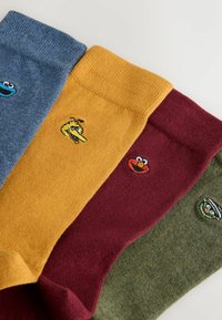 Cztery pary skarpet załogowych w kolorach niebieskim, żółtym, bordowym i zielonym, z kolorowym haftem postaci z kreskówki na kostce.