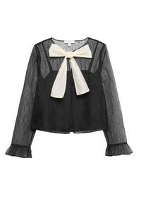 Blusa negra transparente de manga larga, con un lazo blanco en el cuello, tela texturizada y puños con volantes.