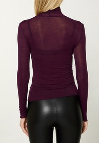 Bordeauxfarbener Langarm-Rollkragenpullover mit figurbetontem Schnitt, aus leichtem, transparentem Material, mit gerafften Details an den Seiten.