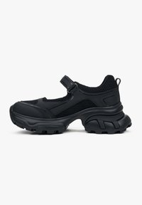 Czarny but sportowy w stylu sneakera, z siateczkową cholewką, masywną gumową podeszwą, regulowanym paskiem oraz fakturowanym wykończeniem po bokach i na pięcie.