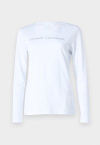 T-shirt manica lunga bianca realizzata in cotone morbido, con la scritta "ARMANI EXCHANGE" in borchie argentate sul petto. Design semplice con scollo a girocollo.