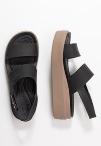 Schwarze Plattformsandalen mit zwei breiten Riemen, einer strukturierten schwarzen Innensohle und einer hellbraunen Gummisohle, die mit einem verstellbaren Schnallen-Detail versehen sind.