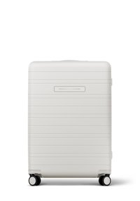 Hartschalenkoffer in mattem Weiß mit horizontalen Rillen, ausziehbarem Griff und vier schwarzen Rollen für Mobilität. Schlanker Kartensteckplatz auf der Vorderseite.