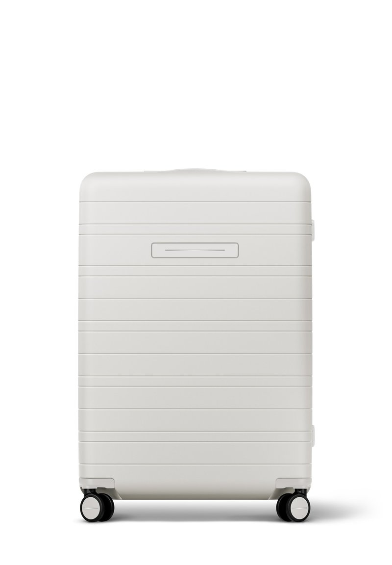 Hartschalenkoffer in mattem Weiß mit horizontalen Rillen, ausziehbarem Griff und vier schwarzen Rollen für Mobilität. Schlanker Kartensteckplatz auf der Vorderseite.