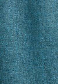 Gros plan d'un tissu tissé turquoise avec une texture visible et une surface légèrement irrégulière.