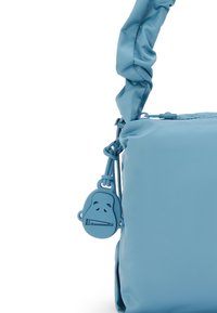 Jasnoniebieska torebka o teksturowej powierzchni, z węzłowym paskiem i dołączonym uchwytem suwaka w kształcie małpki w dopasowanej tonacji.