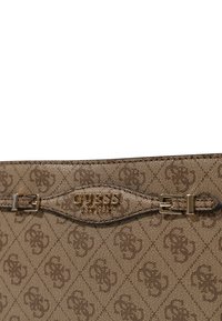Bolso de mano marrón con un patrón, superficie texturizada, herrajes dorados y un logo grabado en el frente; cuenta con un detalle de cierre a presión.