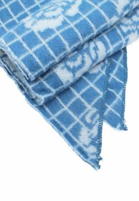 Sciarpa di lana blu con motivo a quadri e accenti bianchi. Texture morbida, bordi cuciti e estremità appuntite.