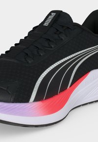 Μαύρο αθλητικό παπούτσι Puma με μαύρα κορδόνια, ασημένιο λογότυπο Puma και λευκή ενδιάμεση σόλα με κόκκινες και μωβ λεπτομέρειες κοντά στα δάχτυλα.