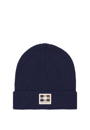 Cappellino blu lavorato a maglia con trama a coste e risvolto. Presenta un'etichetta rettangolare con un motivo a quadretti beige e marrone.