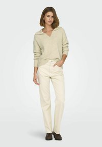Licht beige gebreide trui met een brede kraag, gecombineerd met off-white rechte broek en bruine suède schoenen. Zachte textuur, casual pasvorm.