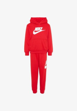 Czerwony dres dziecięcy Nike z kapturem i spodenkami dresowymi, z dużym białym logo Nike na piersi i mniejszym logo na lewej nogawce spodni.