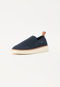 Mornarice slip-on cipela s teksturiranim mrežastim gornjim dijelom, kontrastnim bež kožnim naglaskom i kremasto bijelim gumenom potplatom. Ima šivane detalje duž ruba.