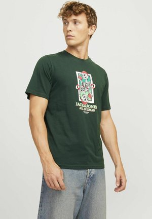 Mørkegrøn bomulds-t-shirt med et farverigt grafiktryk, der viser et kranium og festlige elementer, korte ærmer og rund hals.
