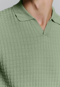 Lichtgroen gebreide polo shirt met een textuurpatroon, V-hals kraag en korte mouwen met een gladde afwerking.