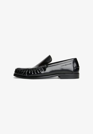 Mocassino nero lucido in pelle con design moc toe cucito e tacco basso, con il logo Tommy Hilfiger sul lato.
