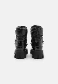 Bottines en cuir verni noir avec tige gonflée, finition texturée, lacets ajustables et semelles en caoutchouc épaisses pour une meilleure adhérence.