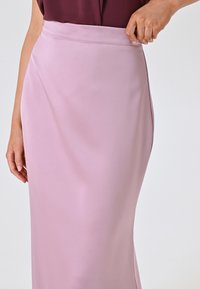 Lange, enganliegende Röcke aus weichem pinkfarbenem Stoff mit glatter Textur und hohem Bund, ohne sichtbare Muster oder Verzierungen.