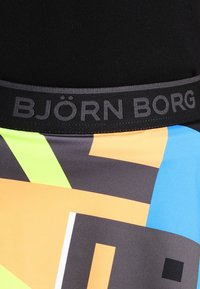 Pestrobarevné šortky s kombinací modrých, oranžových, šedých a zelených geometrických vzorů. Mají černý elastický pas s logem "BJÖRN BORG".
