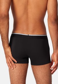 Black boxer briefs with a contrasting gray waistband, made from a smooth, stretchy fabric. Features a fitted design and short leg length.
