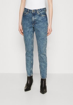 Light blue denim jeans with a straight-leg design, featuring front pockets and a faded texture. Paired with black ankle boots.