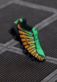 Nike-Sneaker mit einem grünen und orangefarbenen Farbverlauf, Mesh-Obermaterial, schwarzen Akzenten und einer markanten Sohle mit sichtbarem Air-Dämpfungssystem.