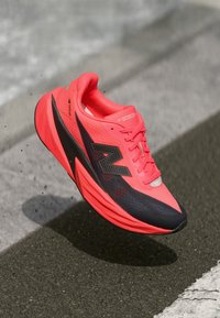 Baskets de running rose vif et noire avec tige en mesh, semelle texturée, logo proéminent et système de laçage ; conçues pour la performance et le confort.