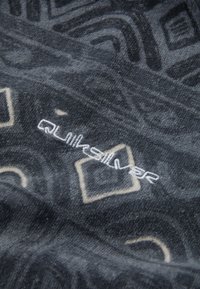 Flis deka s crnom pozadinom i apstraktnim sivim uzorcima. Sadrži bijeli izvezeni "Quiksilver" logo. Meko, teksturirano platno.