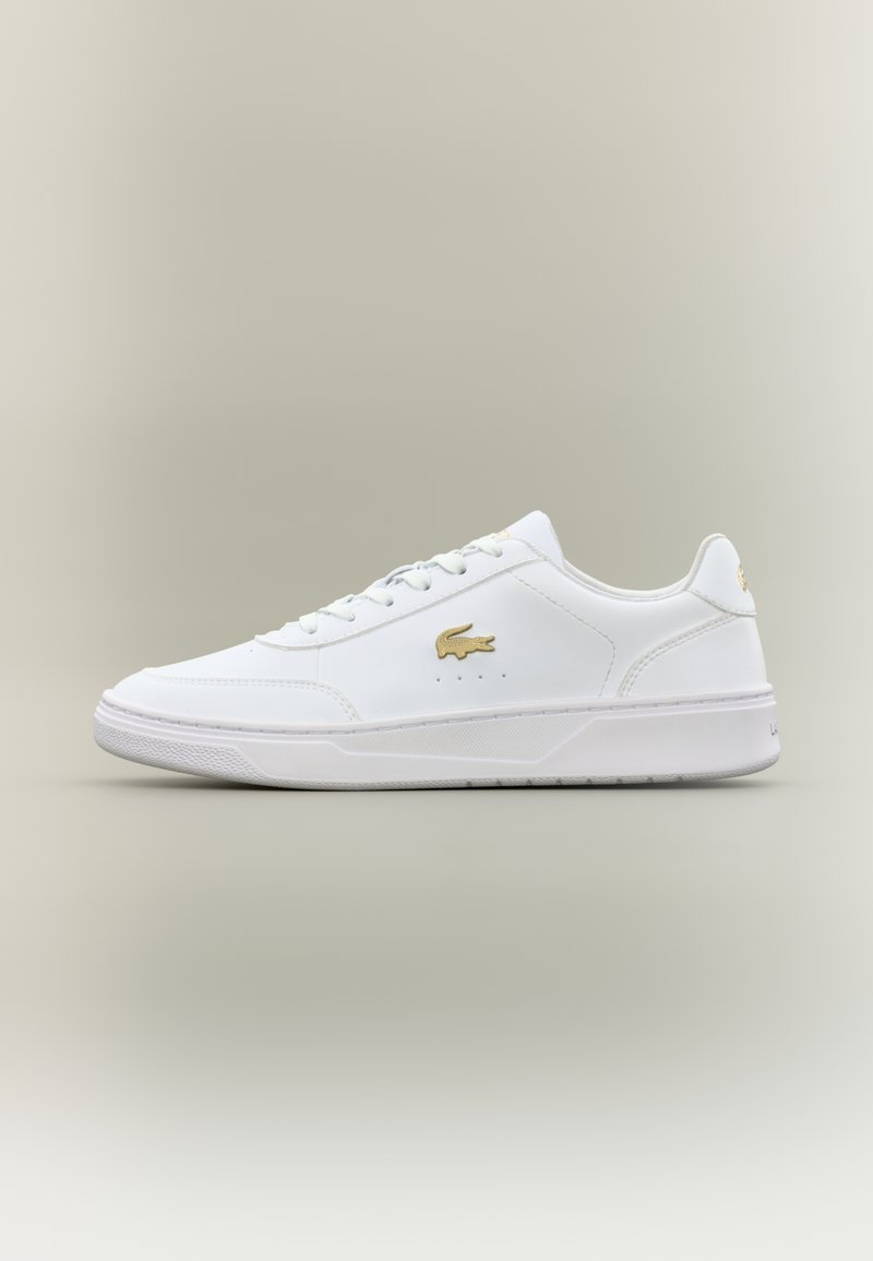 Λευκά δερμάτινα αθλητικά παπούτσια με λεία υφή, που διαθέτουν χρυσό λογότυπο, σχέδιο με κορδόνια και διακριτές τρύπες στο πλάι.