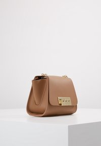 Borsa a tracolla in pelle tan con forma strutturata, chiusura in metallo dorato e una singola tracolla a catena. Texture liscia con design minimalista.